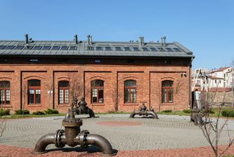 Zrewitalizowany budynek Gazowni w Krakowie z dachem RHEINZINK, otoczony zielenią, prezentujący zrównoważone podejście do architektury i długowieczność materiałów.