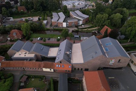 Wąski budynek przytułku i zabytkowa wieża przykryte dachówką z nową częścią centrum "Kult"